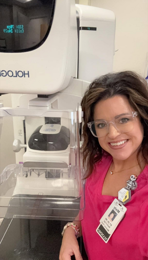 Picture of two females who work in the Mammography Department. One of them is taking a selfie and the other one is in her scrubs standing in front of 3-D Mammography Equipment at Russell County Hospital Women's Health Center